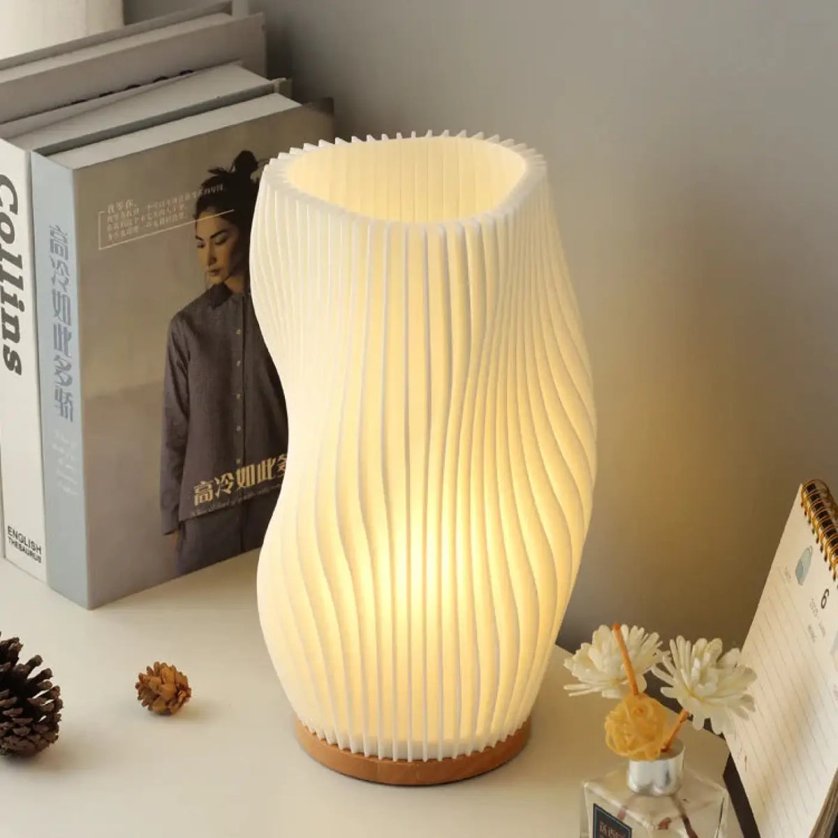 Lampe à poser LOANA blanche nervurée avec socle en bois clair, lumière tamisée sur table de chevet